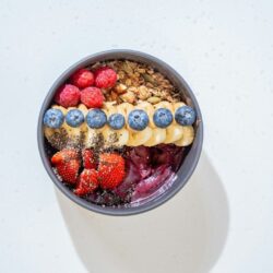 Kulhollinen marjoilla ja siemenillä koristeltua värikästä smoothiekulhoa